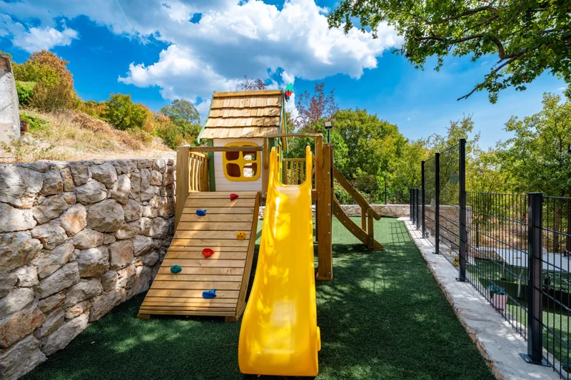 Wooden playhouse with a climbing wall and yellow slide