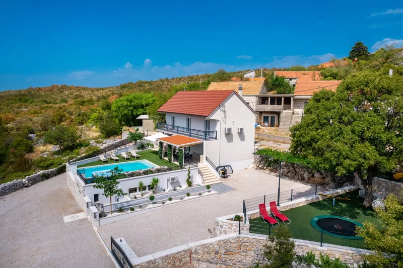 Aerial view of the villa, pool terrace and fenced playground