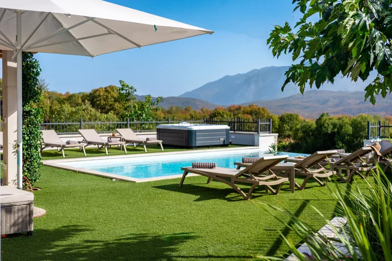 Pool terrace with loungers beneath a parasol and mountain views