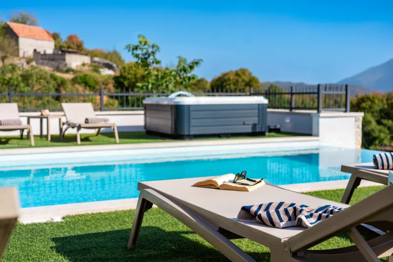 Sun lounger beside the pool with the outdoor Jacuzzi beyond