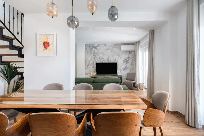 Dining table beneath pendant lights with the living room beyond