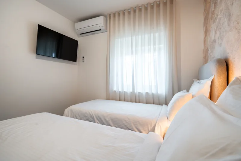 Twin bedroom with a wall-mounted television and air conditioning