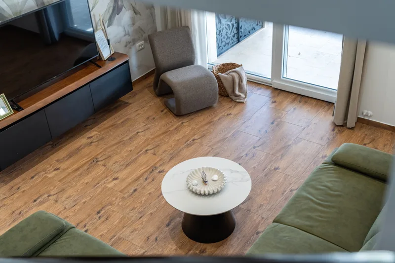 Living room viewed from above, with sofas, a round table and terrace doors