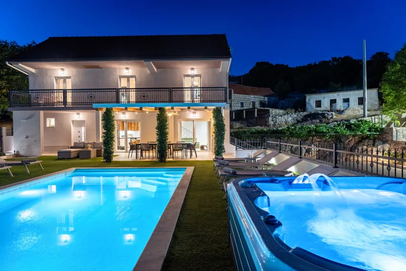 Villa, illuminated pool and Jacuzzi after dusk
