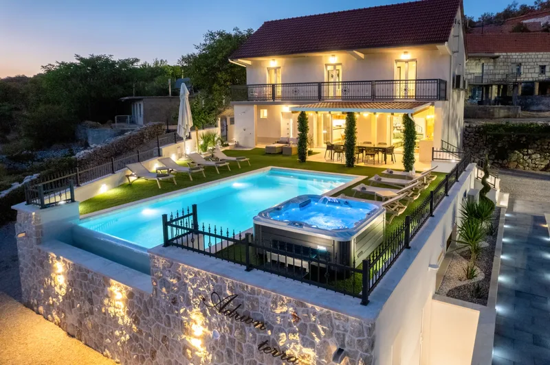 Villa, pool and Jacuzzi illuminated beneath the evening sky